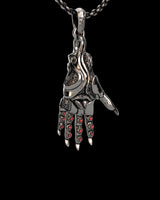 Side angle view of gothic hand pendant showing detailed metalwork and crimson gem placement on silver chain