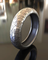 Close-up view of handcrafted sterling silver botanical ring showing intricate vine patterns and oxidized finish details