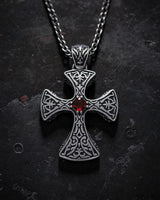 Gold vermeil Celtic cross pendant with red garnet stone and intricate knotwork on dark textured background