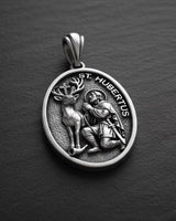 Gold vermeil Saint Hubert pendant showing detailed relief of saint with stag on dark slate background
