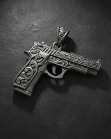 Close-up of ornate pistol pendant with intricate metalwork and decorative patterns on sterling silver