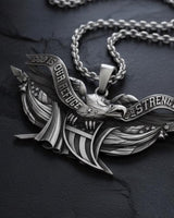 Close-up of handcrafted sterling silver eagle pendant displaying oxidized finish and banner text details