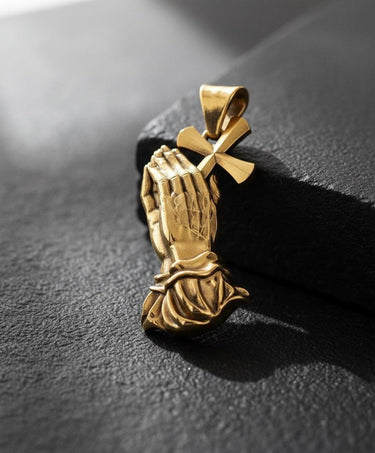 Side angle view of handcrafted praying hands pendant showing detailed cross and sculptural metalwork