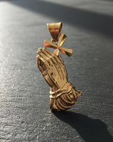 Close-up of gold vermeil praying hands pendant displaying intricate hand positioning and fabric folds