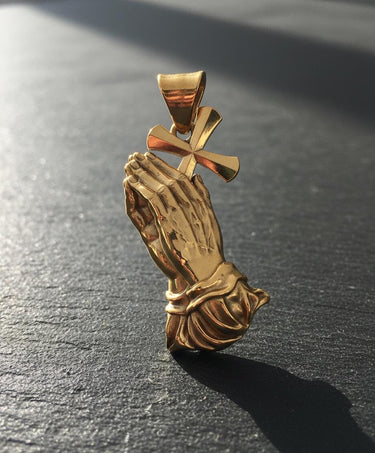 Close-up of gold vermeil praying hands pendant displaying intricate hand positioning and fabric folds