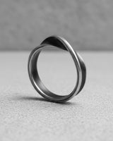 925 sterling silver Mobius ring with twisted infinity band design displayed on textured concrete surface