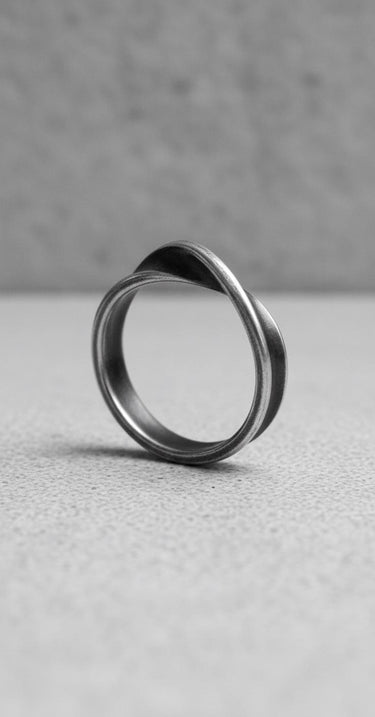 925 sterling silver Mobius ring with twisted infinity band design displayed on textured concrete surface