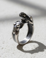 925 sterling silver lovers ring with two intimate figures embracing displayed on textured stone surface