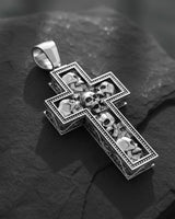 Gothic cross pendant showing intricate skull carvings and ornate border detailing in polished sterling silver