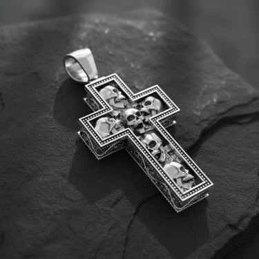 Gothic cross pendant showing intricate skull carvings and ornate border detailing in polished sterling silver