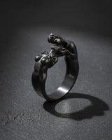 Close-up of sterling silver lovers ring with passionate embrace design on dark background showcase