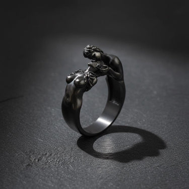 Close-up of sterling silver lovers ring with passionate embrace design on dark background showcase