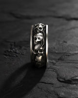 Close-up side view of handcrafted skull ring displaying three-dimensional skull motifs and band detail