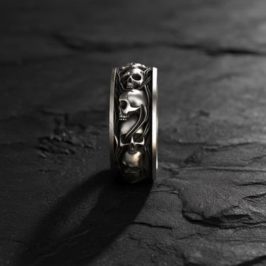 Close-up side view of handcrafted skull ring displaying three-dimensional skull motifs and band detail