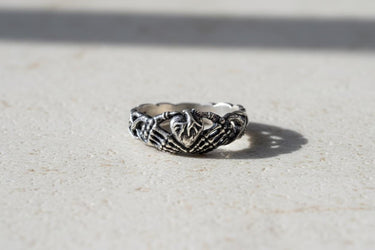 925 sterling silver claddagh skeleton hands ring with intricate bone detailing displayed on dark slate surface