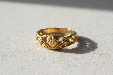 Close-up detail of handcrafted sterling silver skeleton hands ring showing oxidized finish and decorative band elements