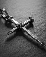 925 sterling silver nail cross pendant with oxidized finish and wire binding detail on dark wood surface