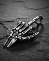 Side view of detailed bone structure pendant with polished sterling silver finish and keychain attachment