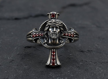 925 sterling silver Jesus cross ring with crown of thorns and ruby gemstones on dark slate background