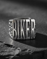 925 sterling silver biker ring with raised BIKER lettering displayed on textured black stone surface