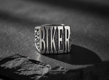 925 sterling silver biker ring with raised BIKER lettering displayed on textured black stone surface