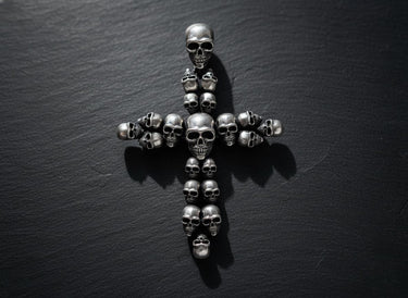 Gold vermeil skull cross pendant with multiple detailed skulls arranged in cross formation on dark slate