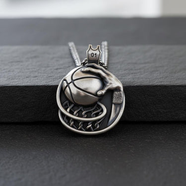 Close-up of polished sterling silver basketball pendant displaying intricate craftsmanship and chain attachment
