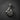 Silver boxing pendant showing championship belt, gloves, and wrapped fist bail, laid flat on a dark slate background.