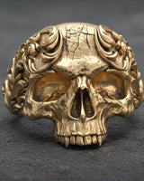 Gold vermeil baroque skull ring showing detailed floral motifs and decorative crown elements on granite