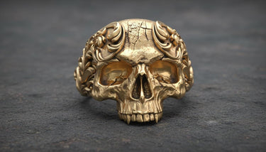 Gold vermeil baroque skull ring showing detailed floral motifs and decorative crown elements on granite