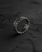 925 sterling silver Celtic knot ring with intricate braided pattern displayed on dark textured stone surface