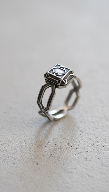 Side angle view of handcrafted geometric ring showing oxidized finish and angular band architectural details