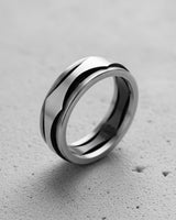 925 sterling silver wave ring with black accent lines displayed on textured concrete surface background