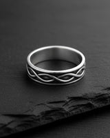 Close-up view of infinity wedding band on black slate showing detailed craftsmanship and polished finish