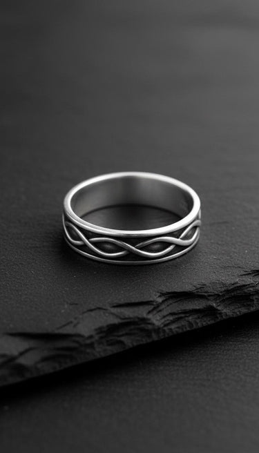 Close-up view of infinity wedding band on black slate showing detailed craftsmanship and polished finish