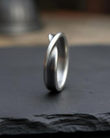 Side angle view of handcrafted Mobius ring showing continuous twisted loop and premium silver finish detail