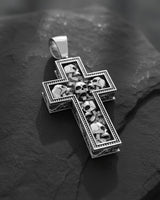 Gold version of skull cross pendant displaying dimensional craftsmanship and detailed metalwork on textured surface