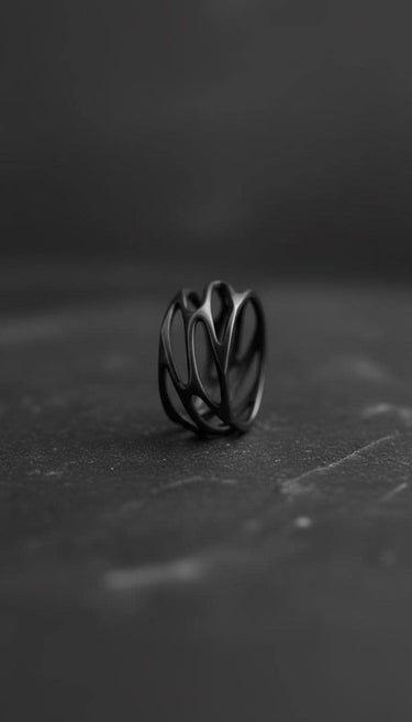 Black rhodium plated sterling silver parametric ring with organic web design displayed on dark stone surface