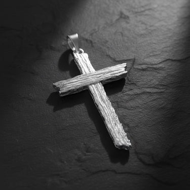 Side angle view of textured cross pendant highlighting the rustic finish and dimensional wood-like pattern design