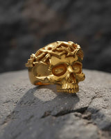 Front view of luxurious 14K gold vermeil skull ring with detailed crown of thorns design on textured stone background