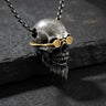 Silver bearded skull pendant with gold vermeil goggles shown at an angle on a dark, textured slate surface for a dramatic look.