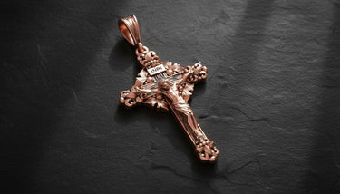 Yellow gold finish Catholic cross pendant showing detailed Jesus Christ figure and baroque scrollwork design