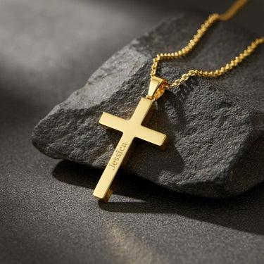 Angled view of a gold personalized cross necklace showing the custom 'Jessica' engraving and the delicate link chain.