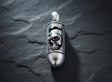 Close-up view of silver skull pendant with ruby red eye accent and bullet-shaped body design