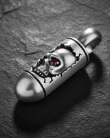 925 sterling silver skull bullet pendant with red gemstone eye on dark textured stone background