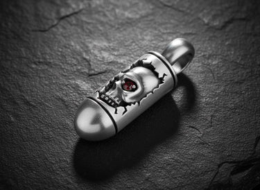 925 sterling silver skull bullet pendant with red gemstone eye on dark textured stone background