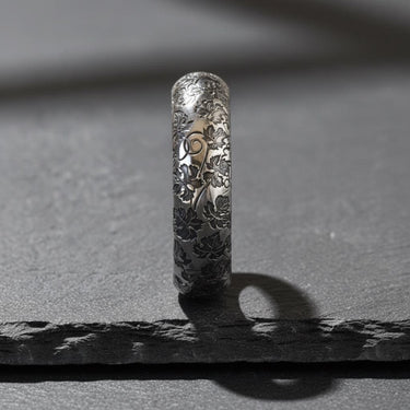 925 sterling silver nature ring with detailed leaf and twig engravings displayed on textured stone surface background