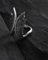 Side view of handcrafted angel wings ring showing detailed feather texture and open band design on black stone