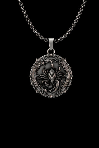 Detailed silver scorpion pendant with an oxidized finish, featuring a central scorpion and ornate gothic border on a chain.