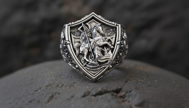 Close-up detail of handcrafted silver dragon ring showing St George on horseback with lance attacking serpent on shield face